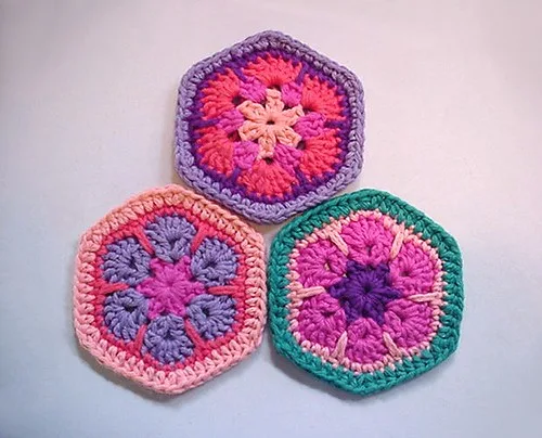 Trois motifs hexagonaux crochetés dans des tons rose, violet et turquoise