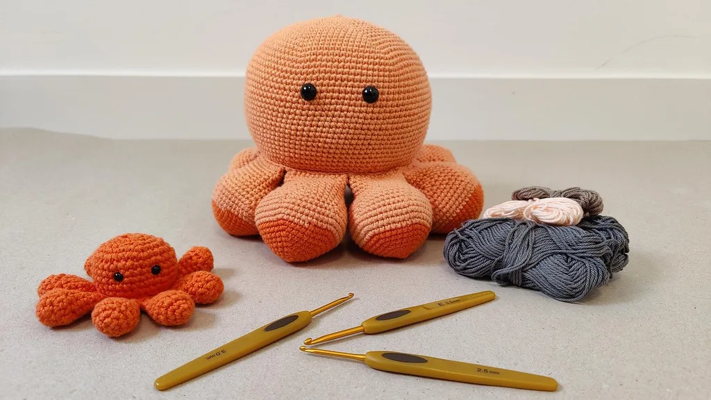 Deux poulpes crochetés, des crochets et des pelotes disposés sur une table